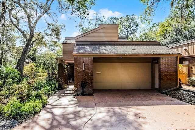 view of front of home featuring a shingled roof, concrete driveway, brick siding, and an attached garage