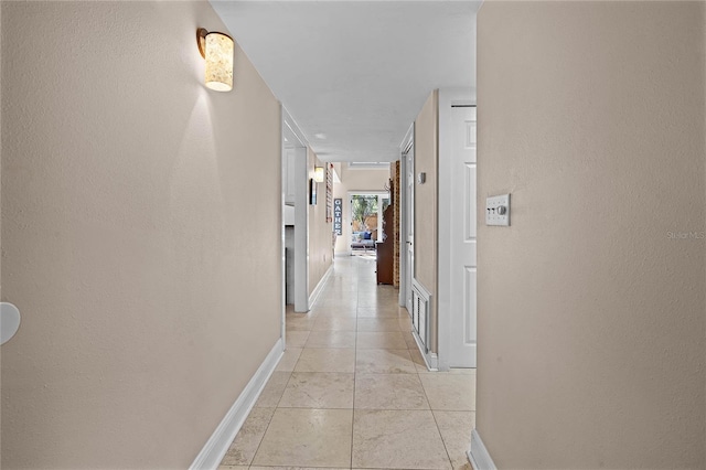 hallway with baseboards and light tile patterned floors