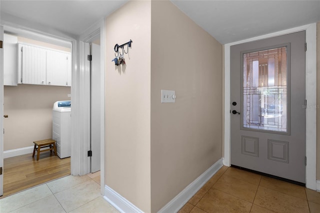 entryway featuring washer / dryer, baseboards, and light tile patterned flooring