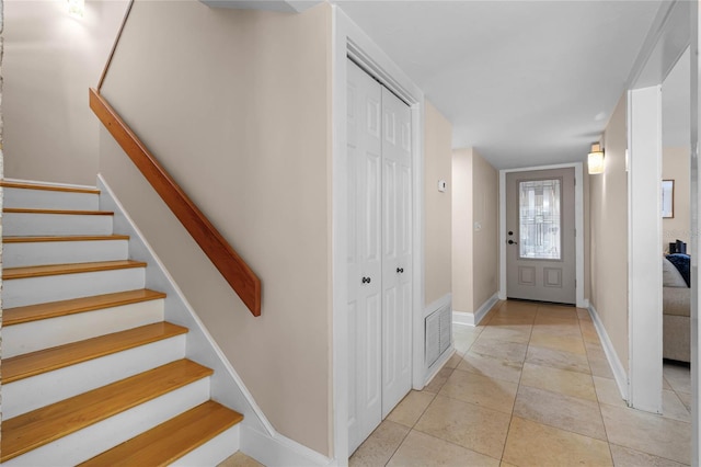 entryway with light tile patterned floors, baseboards, and stairway