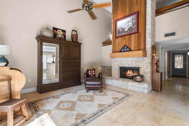 sitting room featuring a brick fireplace, baseboards, a high ceiling, and visible vents