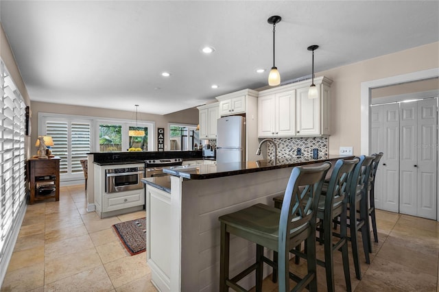 kitchen featuring white cabinets, freestanding refrigerator, a peninsula, pendant lighting, and backsplash