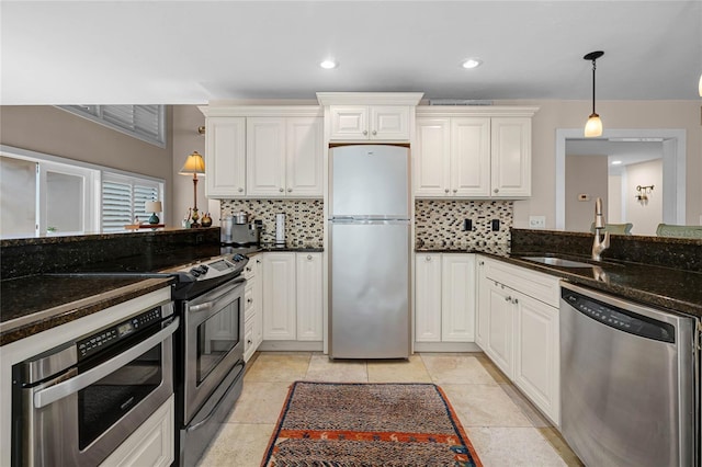 kitchen with a sink, electric stove, stainless steel dishwasher, freestanding refrigerator, and decorative light fixtures