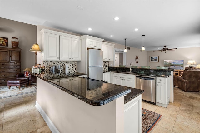 kitchen with tasteful backsplash, appliances with stainless steel finishes, open floor plan, a peninsula, and a sink