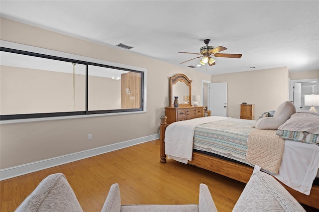 bedroom featuring a ceiling fan, baseboards, visible vents, and wood finished floors