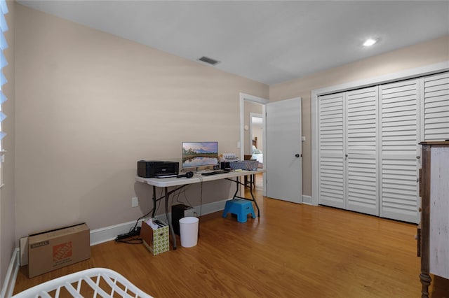 office area with wood finished floors, visible vents, and baseboards