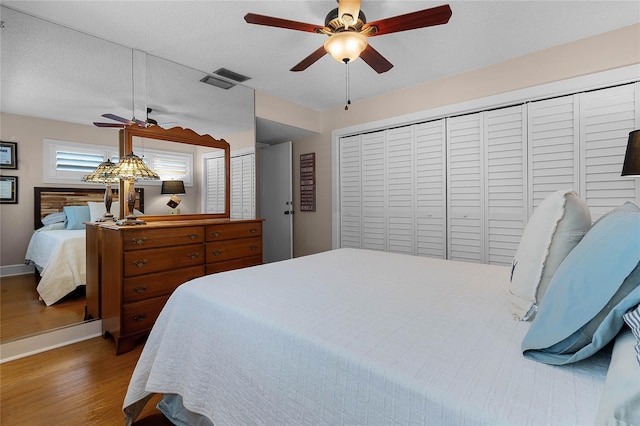 bedroom featuring baseboards, visible vents, ceiling fan, wood finished floors, and a textured ceiling