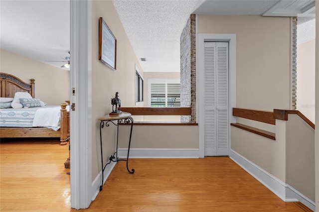 hallway featuring a textured ceiling, baseboards, and wood finished floors