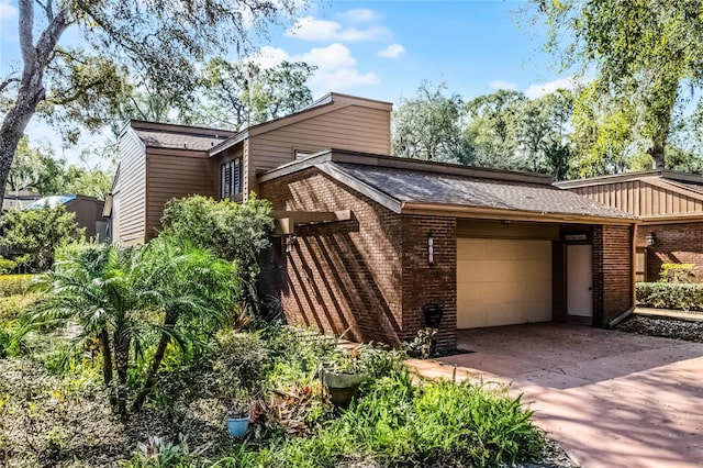 view of front facade featuring a garage, concrete driveway, brick siding, and roof with shingles