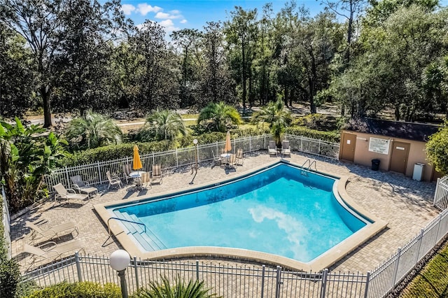 community pool with fence and a patio