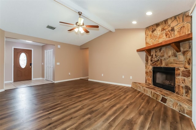 unfurnished living room featuring vaulted ceiling with beams, a stone fireplace, baseboards, and wood finished floors