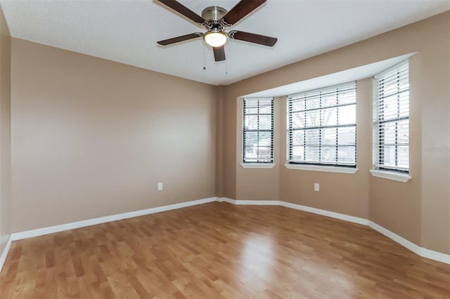 empty room with light wood finished floors, ceiling fan, and baseboards