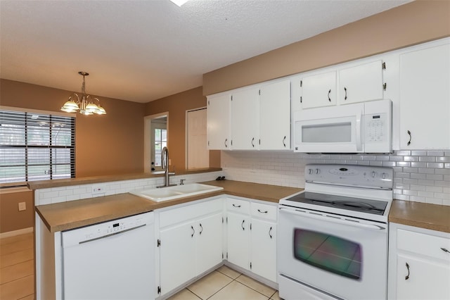 kitchen with decorative light fixtures, white cabinetry, a sink, white appliances, and a peninsula