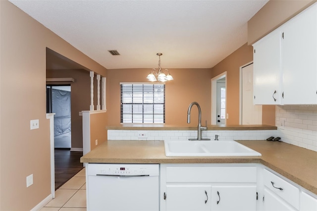 kitchen featuring white dishwasher, a sink, white cabinets, light countertops, and decorative light fixtures