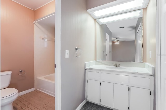 bathroom with toilet, a skylight, vanity, baseboards, and washtub / shower combination