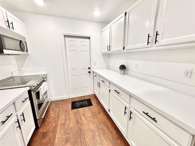 kitchen with white cabinets, appliances with stainless steel finishes, light countertops, and wood finished floors