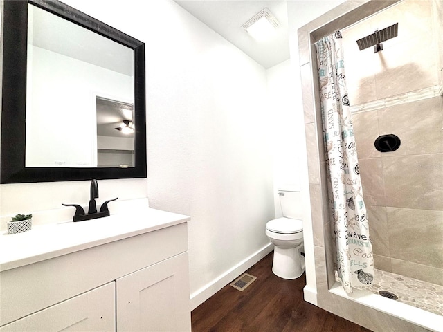 bathroom with visible vents, toilet, a stall shower, vanity, and wood finished floors