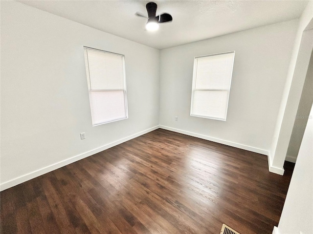 unfurnished room featuring dark wood finished floors, a wealth of natural light, and baseboards