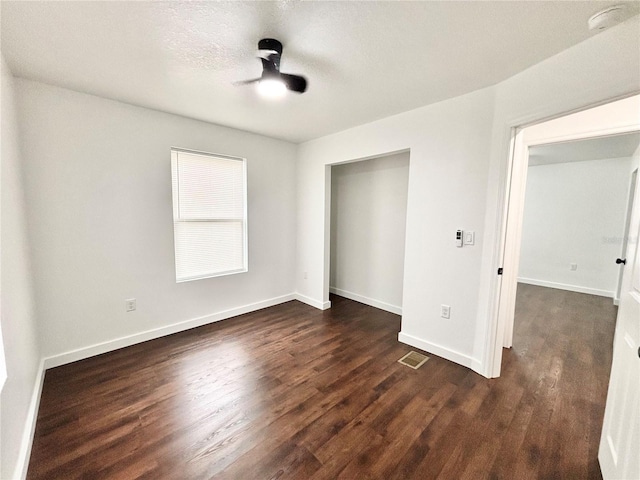 unfurnished bedroom with baseboards, visible vents, dark wood finished floors, a textured ceiling, and a closet