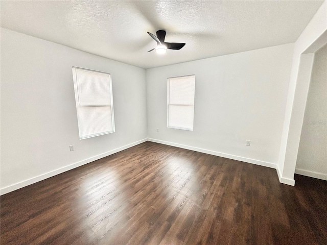 spare room with a textured ceiling, dark wood finished floors, a ceiling fan, and baseboards