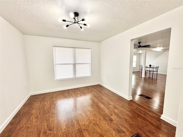 unfurnished room with dark wood-style floors, visible vents, and baseboards