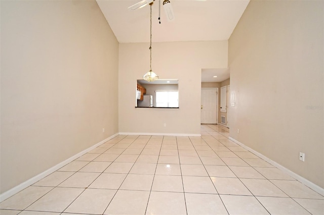 unfurnished room with ceiling fan, a high ceiling, light tile patterned flooring, and baseboards