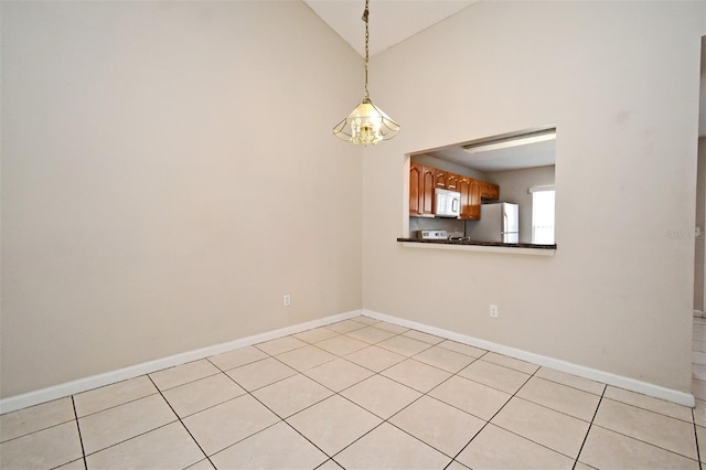 unfurnished room featuring lofted ceiling, baseboards, and light tile patterned floors