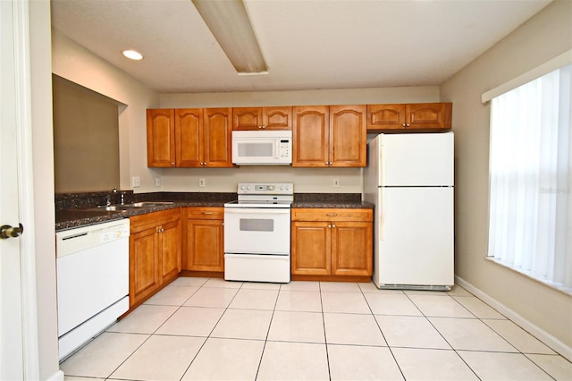 kitchen featuring white appliances, light tile patterned floors, brown cabinets, and a sink