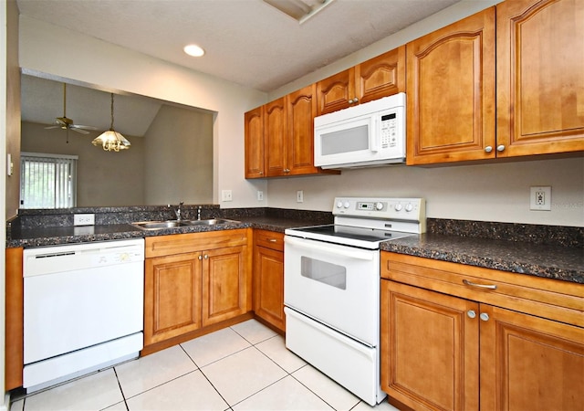 kitchen with light tile patterned floors, white appliances, brown cabinetry, and decorative light fixtures