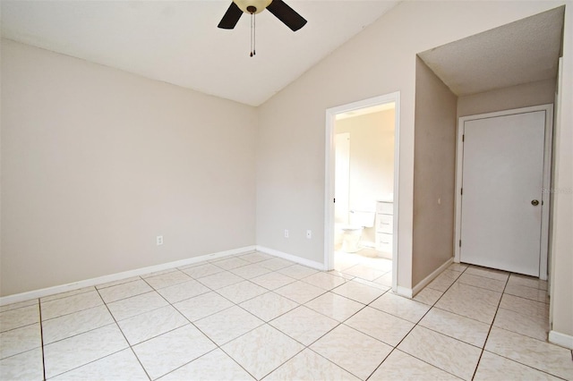 empty room with lofted ceiling, ceiling fan, light tile patterned flooring, and baseboards