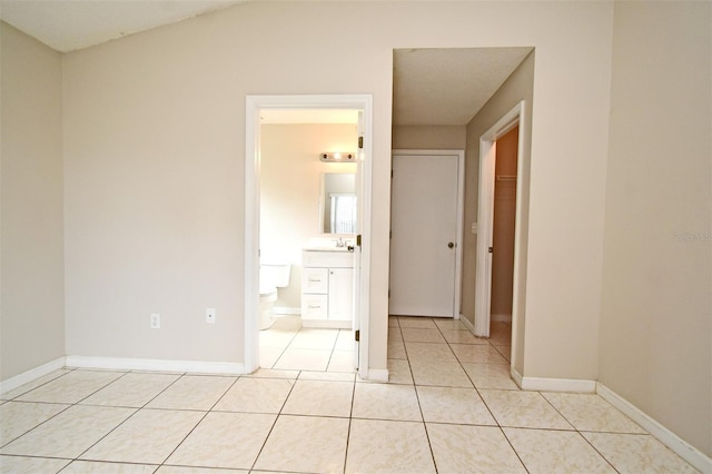 unfurnished bedroom with light tile patterned floors, a sink, and baseboards