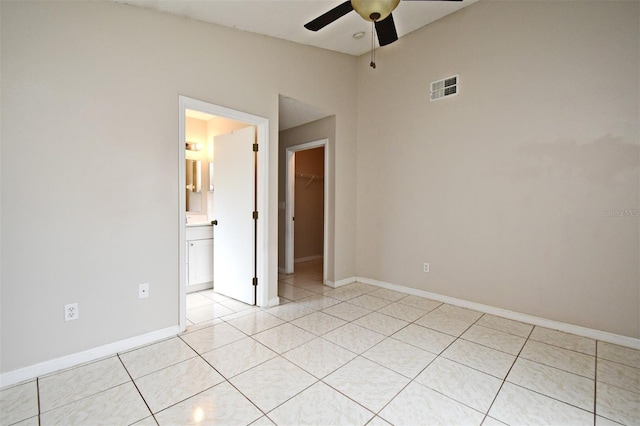 unfurnished bedroom with light tile patterned flooring, visible vents, baseboards, a closet, and a walk in closet