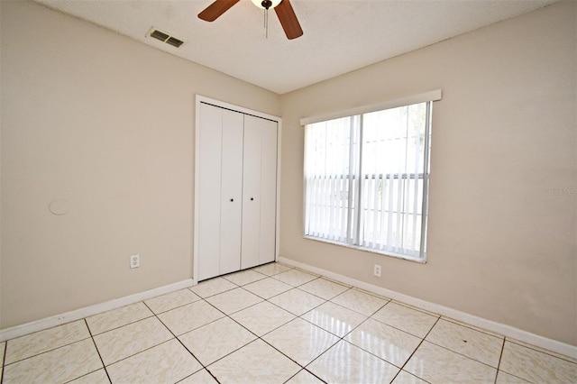 unfurnished bedroom featuring baseboards, visible vents, a closet, and light tile patterned flooring