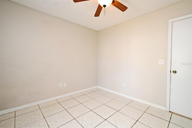 spare room with light tile patterned flooring, a ceiling fan, and baseboards