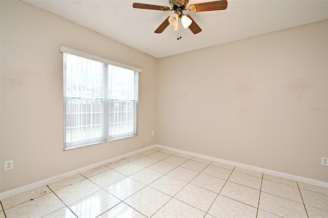 empty room with a ceiling fan, a textured ceiling, baseboards, and light tile patterned floors