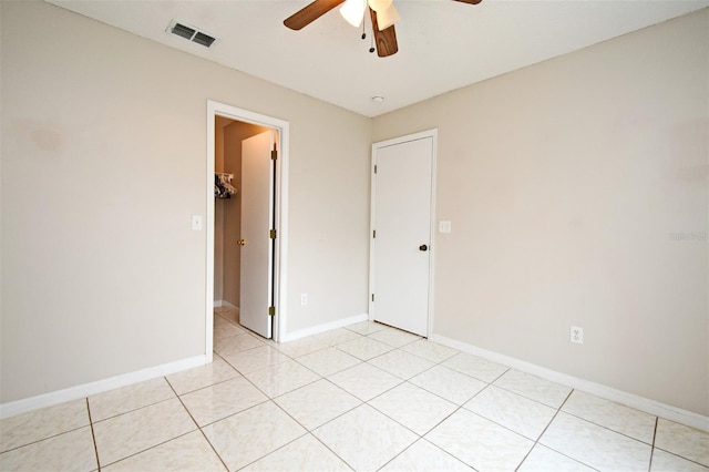 empty room featuring light tile patterned floors, baseboards, visible vents, and ceiling fan