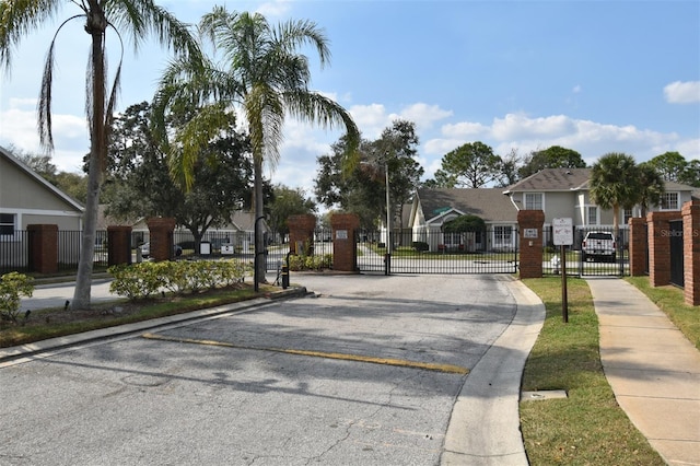 view of street featuring a residential view, a gated entry, curbs, a gate, and sidewalks