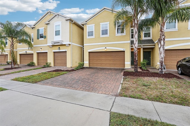 view of property featuring a garage, decorative driveway, and stucco siding