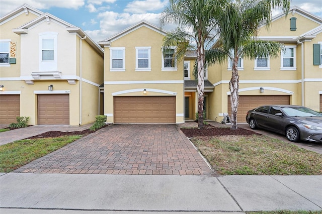 multi unit property featuring an attached garage, decorative driveway, and stucco siding