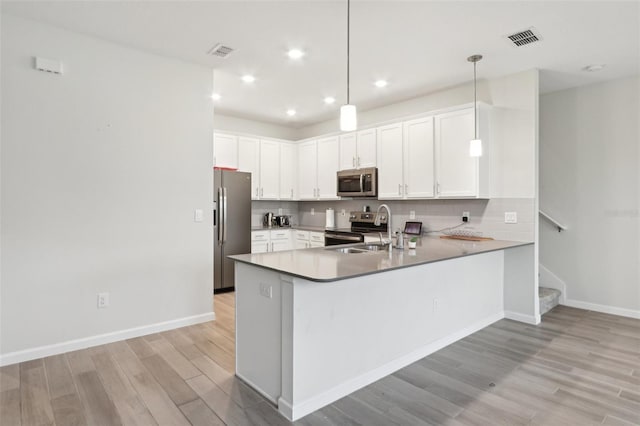 kitchen featuring stainless steel appliances, backsplash, visible vents, and a peninsula