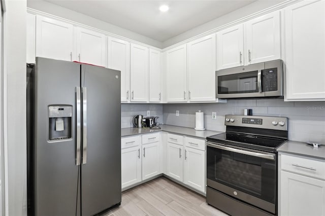 kitchen featuring stainless steel appliances, tasteful backsplash, light wood-type flooring, and white cabinets