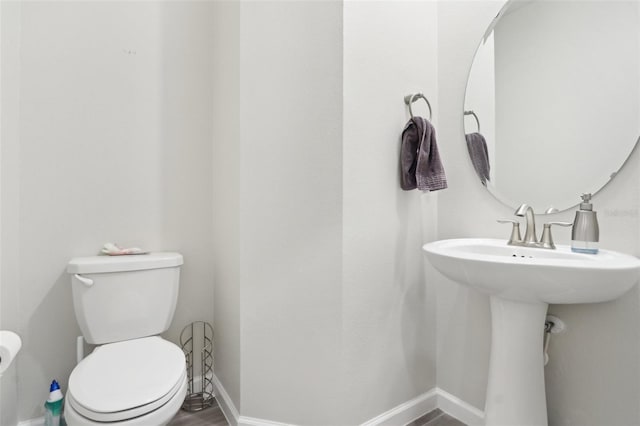 bathroom featuring wood finished floors, toilet, and baseboards