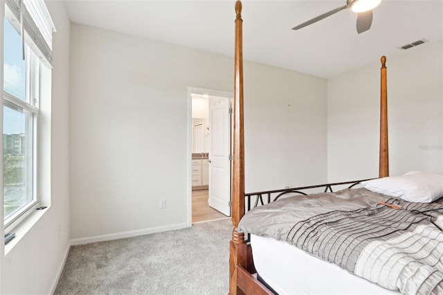 bedroom with carpet floors, visible vents, ensuite bath, and baseboards