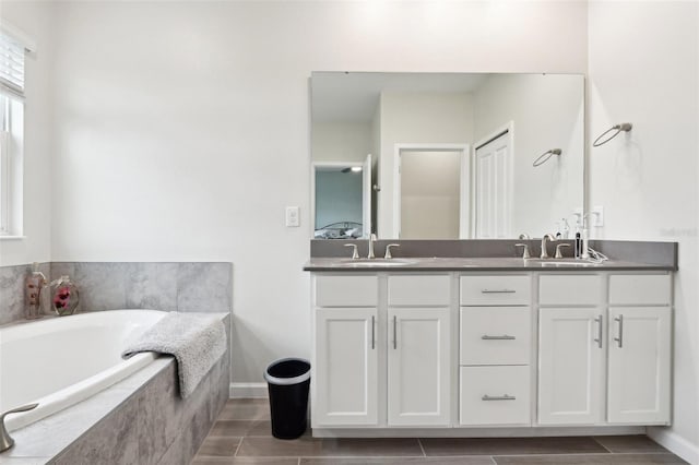 full bathroom with double vanity, ensuite bath, a sink, and a bath