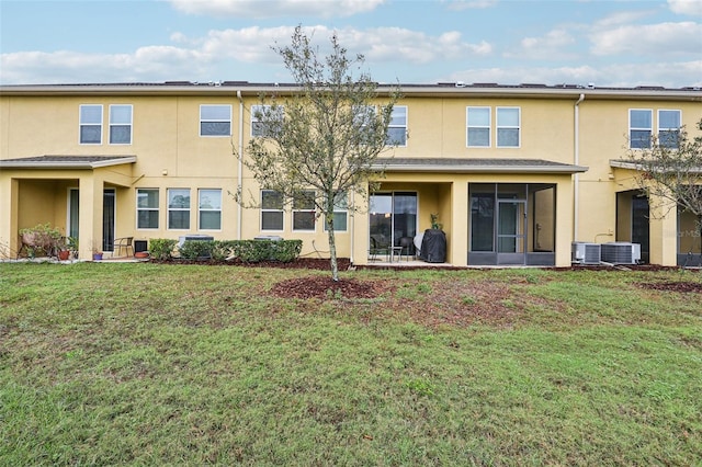 rear view of house featuring a sunroom, cooling unit, a lawn, and stucco siding