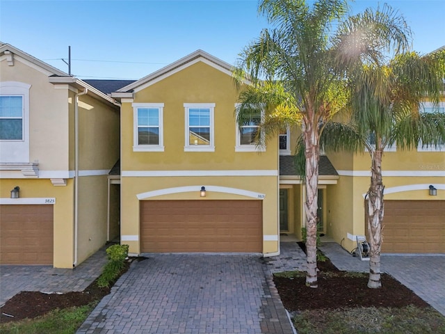 view of property featuring a garage, decorative driveway, and stucco siding