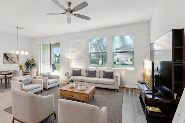 living room with a ceiling fan, baseboards, and wood finished floors