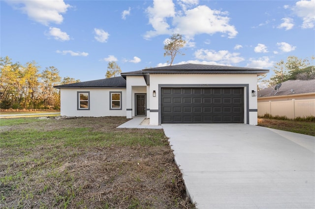 prairie-style house with stucco siding, concrete driveway, an attached garage, fence, and a front lawn