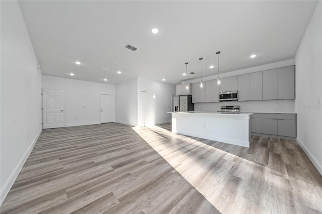 kitchen with light countertops, visible vents, appliances with stainless steel finishes, a kitchen island, and modern cabinets