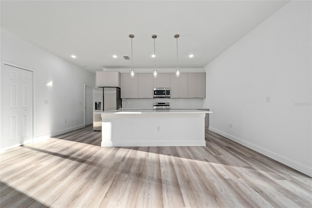 kitchen featuring pendant lighting, stainless steel appliances, light countertops, a kitchen island, and modern cabinets